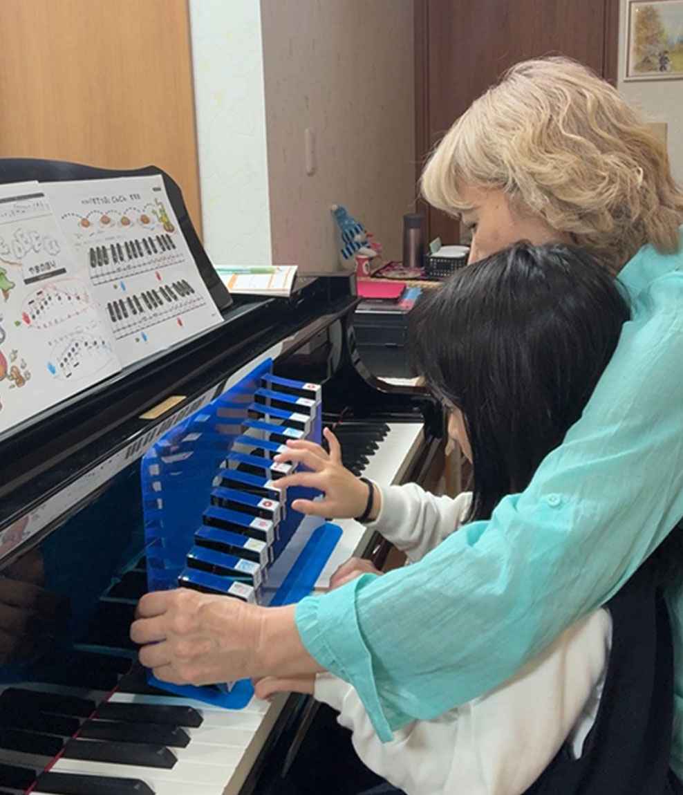 先生と一緒に鍵盤を見る子ども