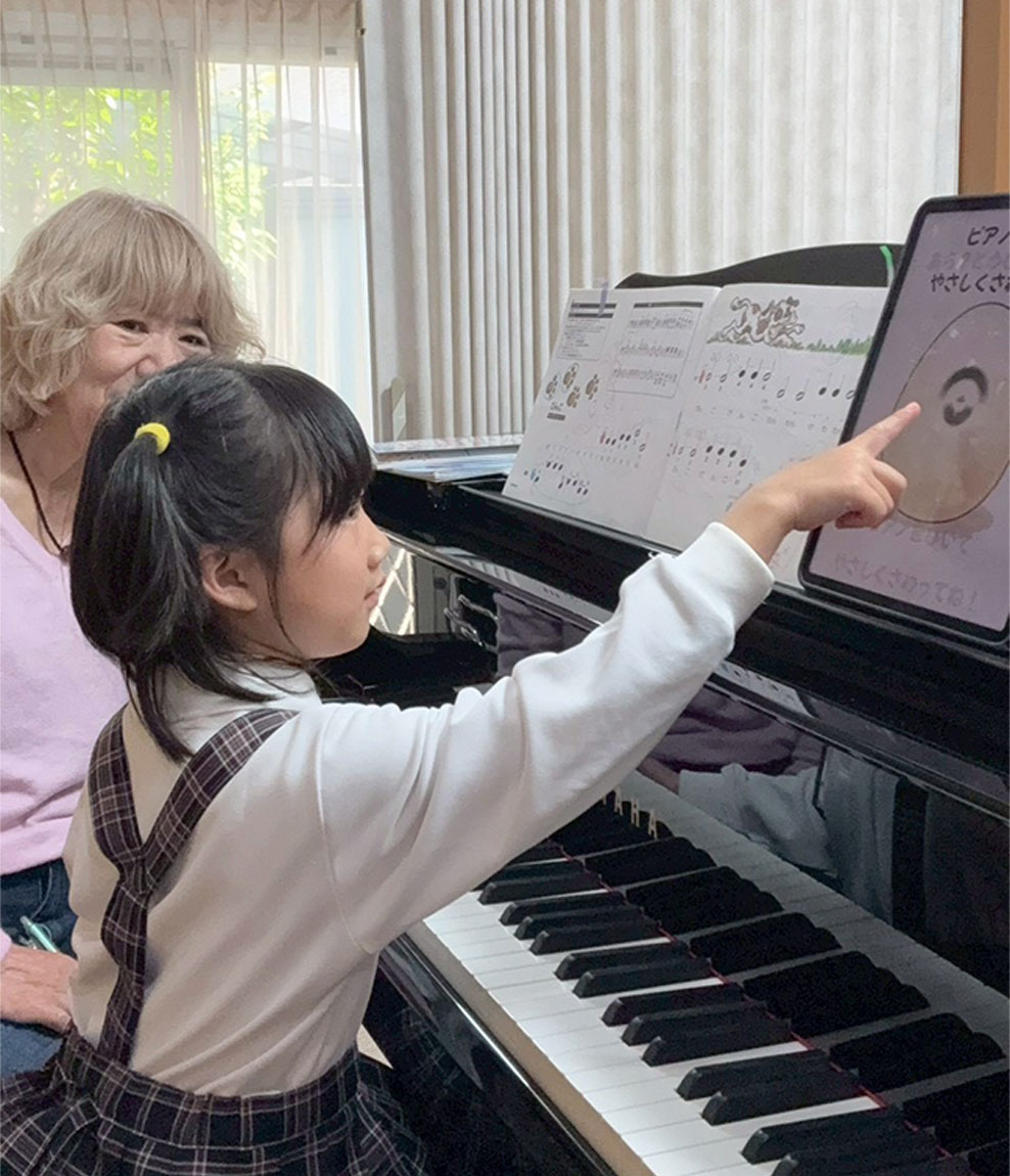 先生の指導を受けながらピアノに向かう生徒